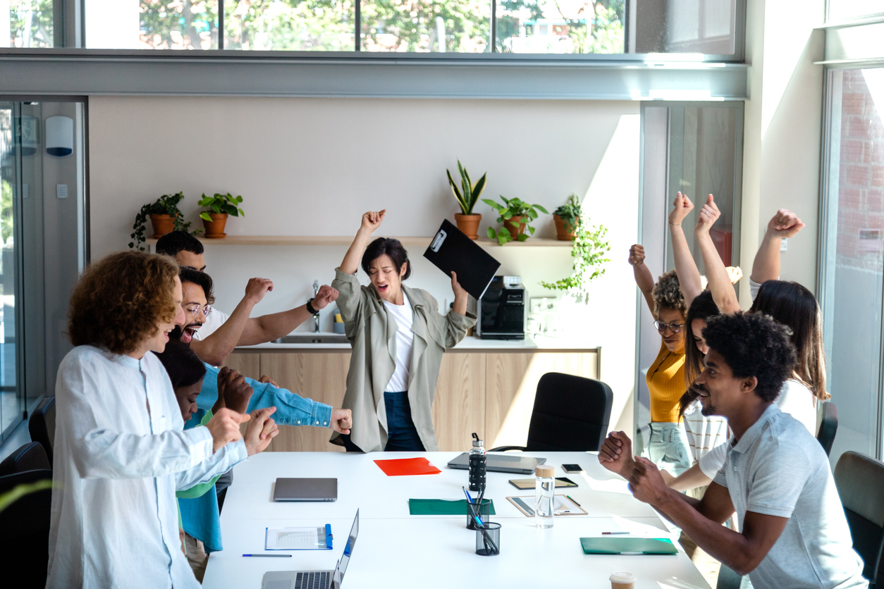 Multiracial coworkers and female hispanic boss dance in the office celebrating company results. Copy space. Multiracial coworkers and female hispanic boss dance in the office celebrating company results. Copy space. Business success concept.